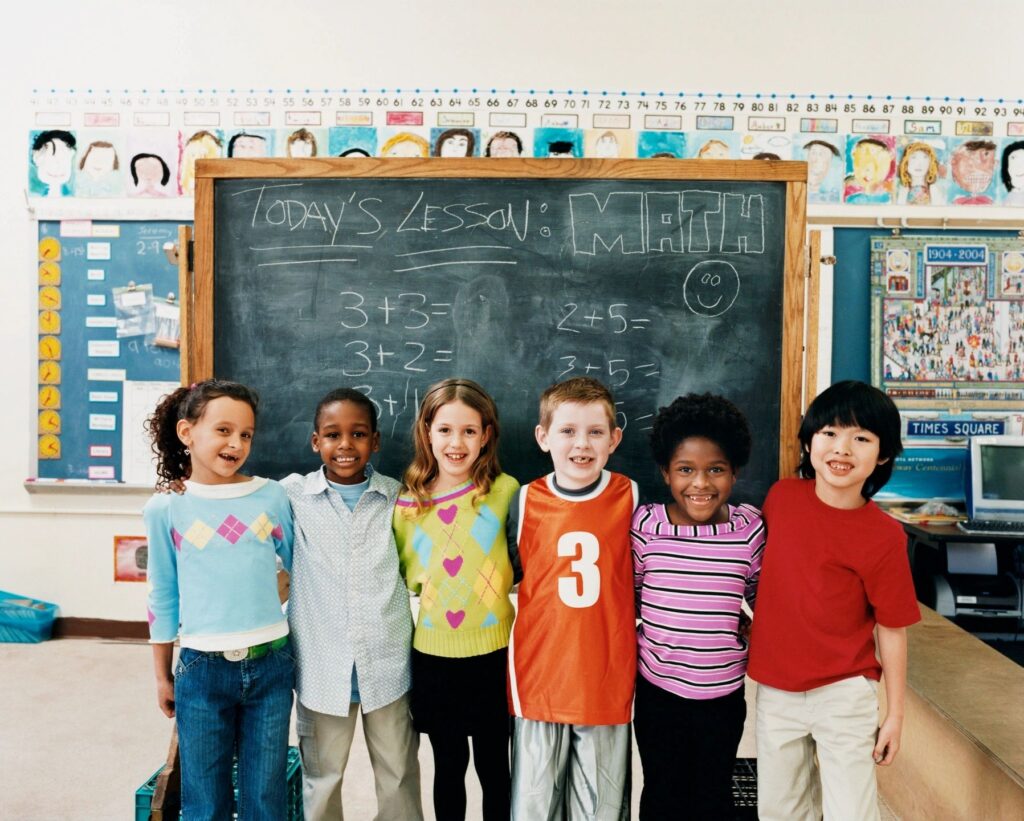 A bunch of kids standing together in front of a blackboard